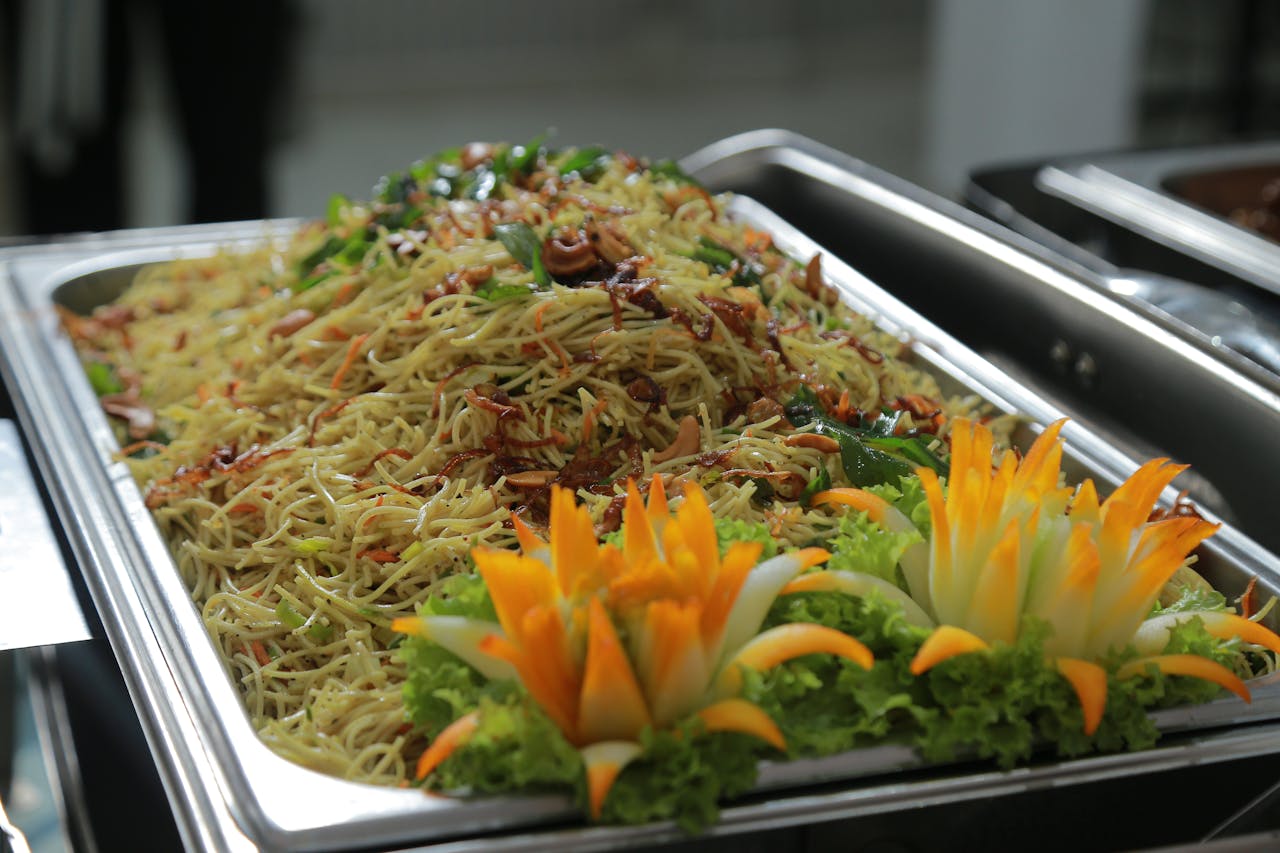 A vibrant display of Sri Lankan noodles garnished with fresh vegetables and artistic carvings.